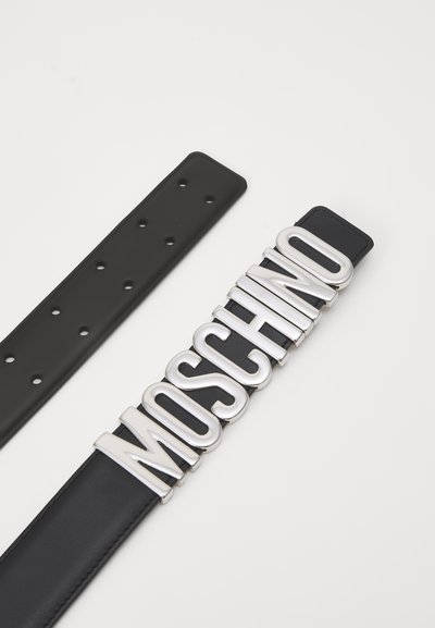 Svart lærbelte med en bred metallisk sølvfarget "MOSCHINO" logo spenne. Reimen har flere hull for justerbar passform.