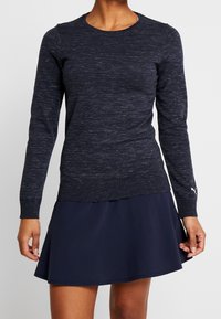 Navy long-sleeve sweater with a textured finish and ribbed cuffs, paired with a dark navy flared skirt. Features subtle detailing on the sweater.
