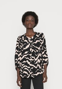 Blusa preta e creme com padrão, mangas três quartos, decote redondo e fecho de botão. Tecido suave e corte solto.