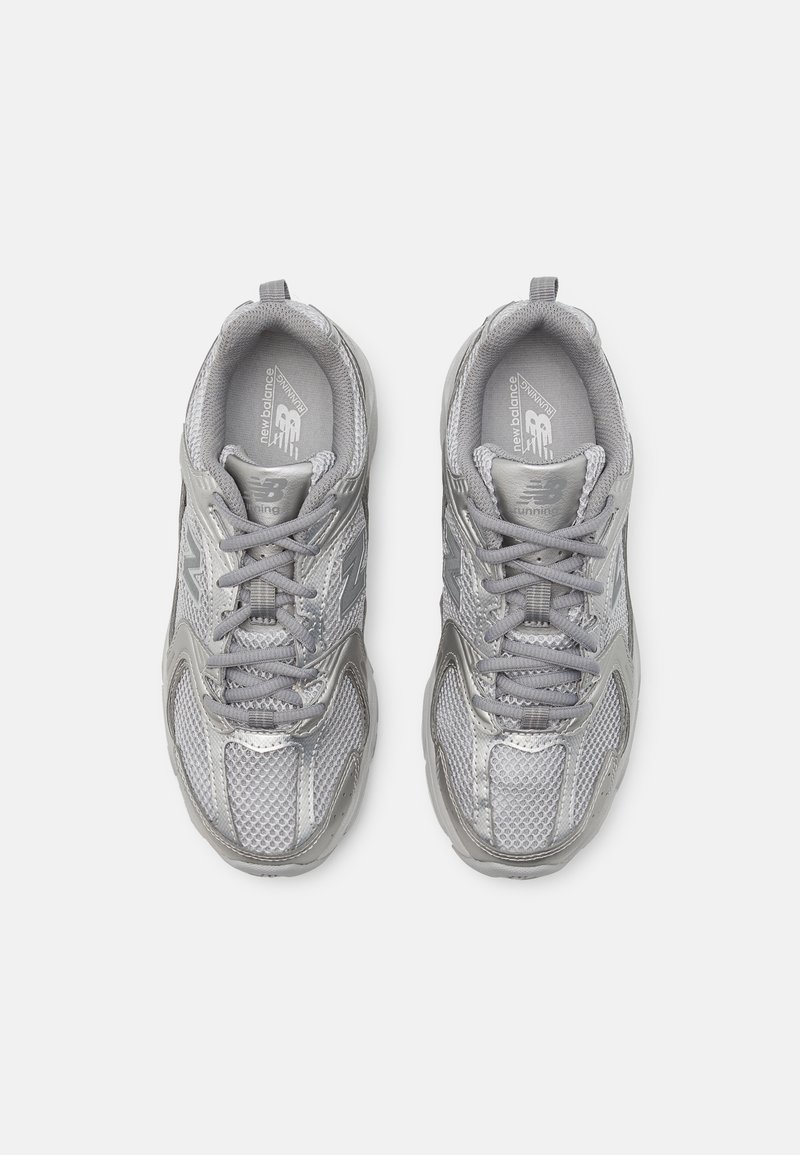 Srebrne sportowe sneakersy z siateczkowymi i syntetycznymi nakładkami, zaokrąglony czubek, sznurowane zapięcie, wyściełany kołnierz oraz akcenty z logo po obu stronach.