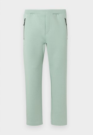 Ανοιχτά πράσινο παντελόνι με ίσια γραμμή, ελαστική μέση και πλαϊνές τσέπες με φερμουάρ σε απλό λευκό φόντο.