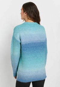 Helles blaues Gradient-Pullover mit geripptem Muster, ausgestattet mit Rundhalsausschnitt und langen Ärmeln. Die Farbe wechselt von hellblau zu dunkelblau.