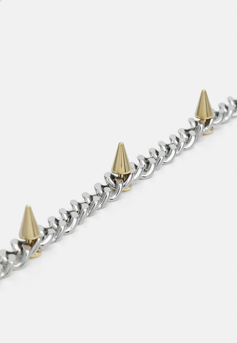 Bracciale in metallo a catena con anelli alternati in argento e punte a forma di cono dorate, che mette in mostra un mix di texture lucide e forme distintive.