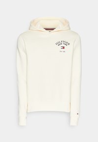 Hoodie color crema realizzato in morbido tessuto, con un grande logo frontale che riporta "HILFIGER NEW YORK" e la data di fondazione. Include una tasca a marsupio.