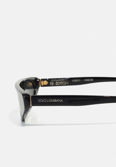 Juodi akiniai nuo saulės su blizgiu paviršiumi. Papuošti auksiniais akcentais ir išgraviruotu „DOLCE & GABBANA“ ženklu ant šventyklos.