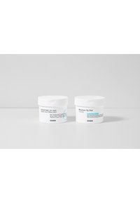 Twee witte ronde containers met het label "Moisture Up Pad," met een minimalistisch ontwerp in zwarte tekst en blauwe accenten.