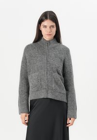 Gray knitted zip-up sweater with high collar, ribbed cuffs, and two front pockets. Soft texture, cropped design, minimalistic style.