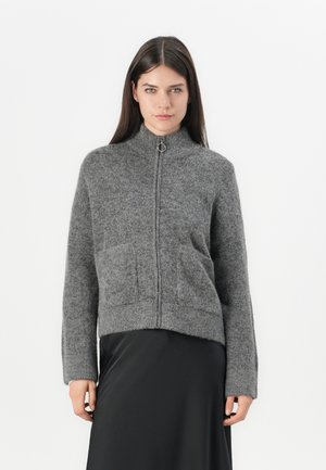 Pull gris en maille à fermeture éclair avec col haut, poignets côtelés et deux poches avant. Texture douce, design court, style minimaliste.