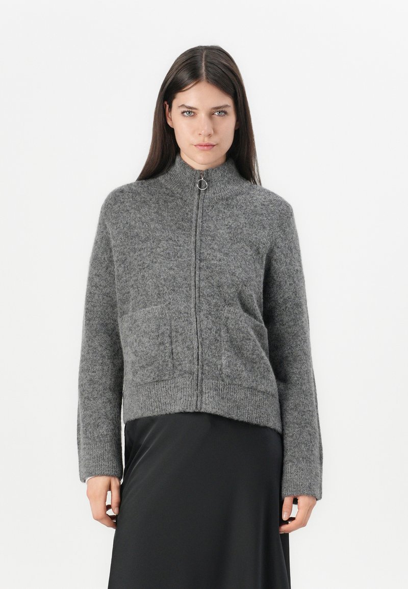 Gray knitted zip-up sweater with high collar, ribbed cuffs, and two front pockets. Soft texture, cropped design, minimalistic style.