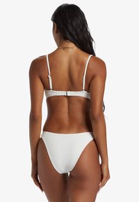 White ribbed bikini with adjustable straps and a clasp closure at the back, featuring high-cut bottoms and smooth texture.