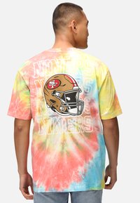 Pastellfärgad tie-dye kortärmad t-shirt med San Francisco 49ers hjälm grafik och texten "Niners" i vitt på baksidan.