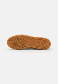 Barna gumi talp, textúrázott tapadásmintával, ASICS logóval. Simított élek és párnázott kialakítás fokozza a kényelmet és a stabilitást.