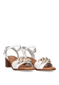 Sandalias de tacón blancas de cuero con un diseño de tiras, que presentan un detalle decorativo de cadena metálica en la parte frontal y un tacón marrón.