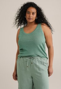 Top sin mangas de color verde menta con relieve, con tirantes anchos y un escote redondeado, combinado con pantalones de tiro ajustable de color verde claro a juego.