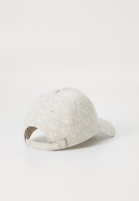 Beige baseball cap with a subtle all-over pattern, adjustable strap at the back, and a soft, textured fabric finish.