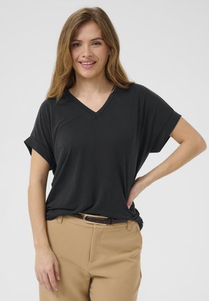 T-shirt nera a maniche corte con scollo a V realizzata in tessuto morbido, abbinata a pantaloni beige e una cintura marrone con una fibbia dorata.