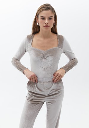 Helles graues Samtbodysuit mit einem quadratischen Ausschnitt und langen Ärmeln. Hat Raffung an der Brust und eine glatte Textur. Kombiniert mit passenden Hosen.