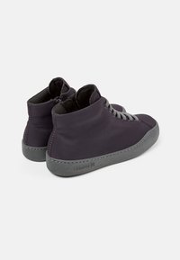 Dunkellila knöchelhohe Sneakers mit einem glatten Textilobermaterial und grauen Gummisohlen. Sie verfügen über graue Schnürsenkel und dezente Markenkennzeichnung an der Seite.