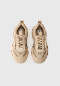 Beige athletic shoes featuring a mix of suede and mesh materials, padded tongue, laces, and textured rubber sole with prominent detailing.