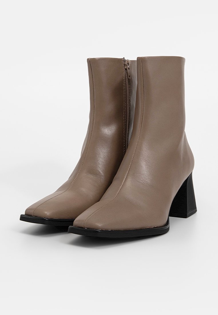 Beige leren enkellaarsjes met een vierkante neus, zijrits en blokhak. Soepele textuur met een matte afwerking en zwarte zool.