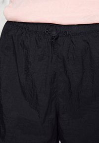 Czarne szorty wykonane z lekkiego materiału o fakturowanej powierzchni, z elastycznym pasem i sznurkiem do regulacji.