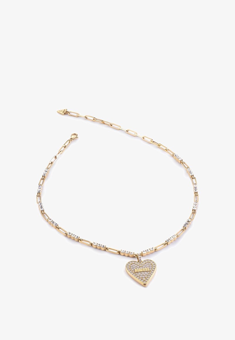 Collier chaîne en or avec des maillons rectangulaires et des cristaux incrustés, avec un pendentif en forme de cœur recouvert de petits cristaux et une plaque du nom de la marque.