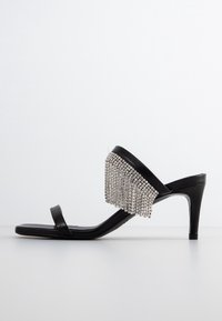 Svarta högklackade sandaler med en stilren design, prydda med fransdetaljer av silverfärgade rhinestones. Släta läderspännen fulländar utseendet.