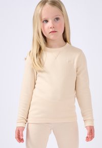 Beige lange mouwen top met een geribbelde textuur, ronde halslijn en subtiele stiksels, gecombineerd met bijpassende broek in dezelfde kleur.