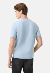 Light blue short-sleeve t-shirt made of soft fabric with a crew neckline, featuring a smooth texture and a relaxed fit. Back view.