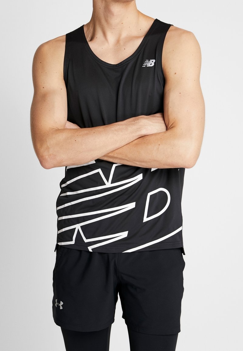 Czarny sportowy top na ramiączkach z geometrycznym białym wzorem, wykonany z lekkiego materiału. Nosi się go z czarnymi szortami, które mają logo Under Armour.