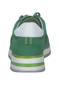 Grüner Sneaker mit einem glatten Textiloberteil, weißem Fersenbereich, gemustertem Zungenbereich und grünen Akzenten an der Sohle. Rundlicher Zehenbereich und gepolsterter Schaft.