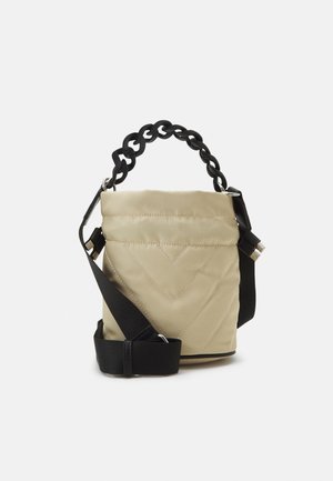 Beige quiltet bøtte taske med sort chunky kædehåndtag og justerbar sort skulderrem på hvid baggrund.