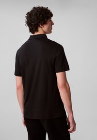 Crna polo majica s kratkim rukavima, klasičnog ovratnika i glatke teksture, s bočnim prorezima na rubu za lakše kretanje.