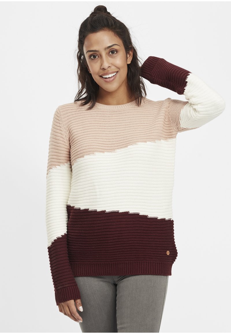 Pull en tricot avec un design rayé en rose poussiéreux, crème et bordeaux. Texture côtelée avec un col rond et des poignets allongés.