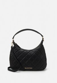 Vadderad svart läderhandväska med en axelrem och guldfärgad metall. Har en böjd form och "Valentino"-logotyp på framsidan.