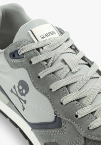 Graue Sneaker mit Obermaterial aus Wildleder und Stoff, ausgestattet mit einem Totenkopf-Graphic, strukturierten grauen Schnürsenkeln und einem weißen Etikett mit "Scalpers"-Branding.