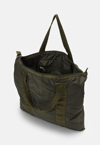 Sac fourre-tout vert olive en tissu durable, doté d'un intérieur spacieux, de deux poignées de transport et d'une fermeture éclair.