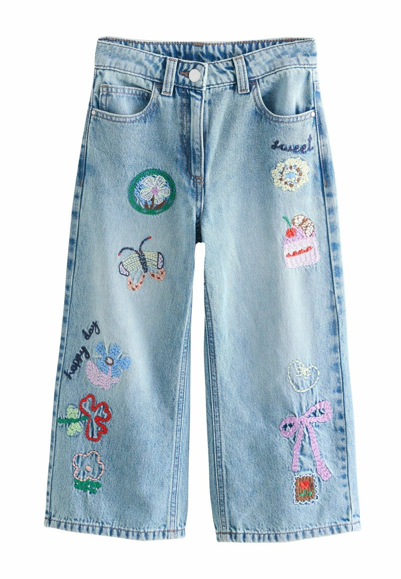 Jasnoniebieskie szerokie dżinsy z denimu ozdobione kolorowymi haftowanymi naszywkami z kwiatami, motylem i ciastem na przedzie.