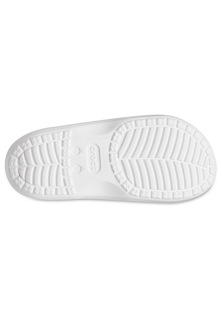 Semelle de chaussure en caoutchouc blanc présentant un design texturé avec des rainures, des grips circulaires et des motifs triangulaires pour l'adhérence.