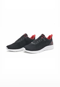 Scarpe sportive nere con accenti rossi, parte superiore in mesh, suola bianca e design con lacci. Presentano un motivo testurizzato sul lato e un colletto imbottito.