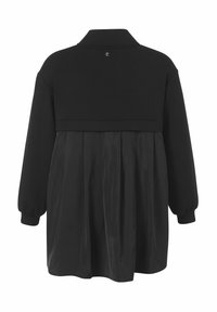 Zwarte jurk met een aansluitend bovenstuk met kraag, lange mouwen en een plissérok. Gemaakt van een mix van sweatshirt- en gladde stoftexturen.