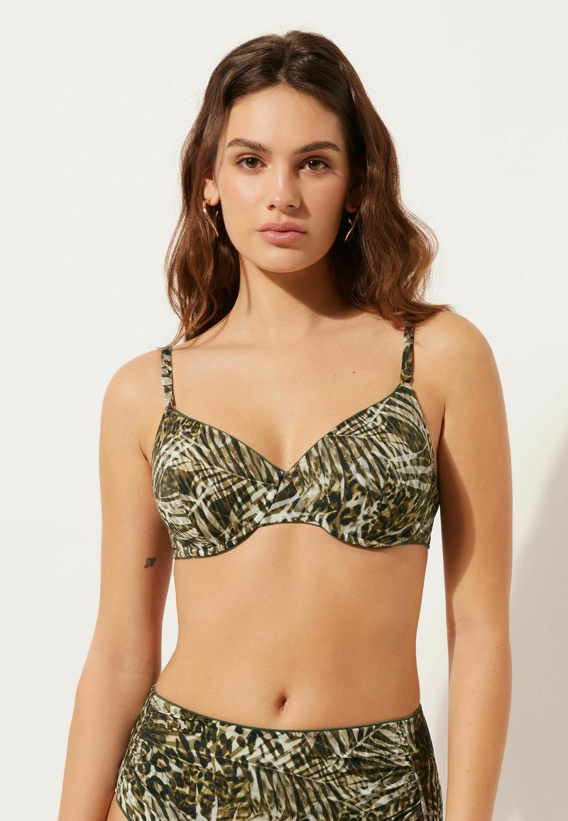 Bikiniöverdel i ett grönt och brunt tropiskt bladmönster, med djup V-ringning, justerbara axelband och mjukt tyg.