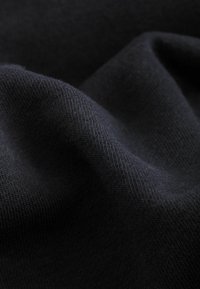 Schwarzer Stoff mit einer glatten Textur, leicht gedehnt, mit einem feinen Strickmuster. Die Oberfläche erscheint weich und matt mit wenig Glanz.