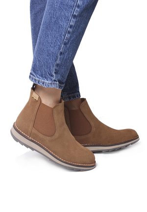 Brown suede Chelsea boots with elastic panels, round toes, and a rubber sole. Features stitching along the edges and a fabric pull tab at the heel.