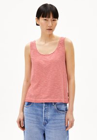 Red and white striped tank top with a scoop neckline and wide straps, made of lightweight fabric. Paired with loose blue denim shorts.