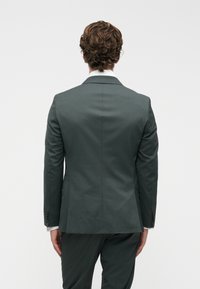 Γκρίζο σακάκι με λεία υφή, μονό αεραγωγό και κομμένα πέτα. Διαθέτει κουμπωτές μανσέτες και δομημένη γραμμή.