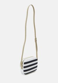 Pruhovaná taška přes rameno s bílým základem a námořnickými pruhy, vyrobená z hladkého materiálu, s nastavitelným béžovým popruhem a zipovým uzávěrem.