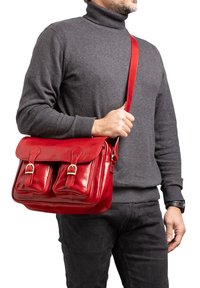 Borsa a messaggero in pelle rossa con fibbie in metallo, dotata di due tasche frontali, una lunga tracolla regolabile e una texture liscia e lucida.
