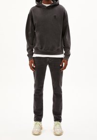 Tmavě šedá mikina s kapucí a přední kapsou, spárovaná s tmavými džíny a multicolor teniskami s akcenty a texturovanou podrážkou.