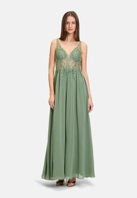 Robe longue verte avec un décolleté en V, un corsage en tulle orné de perles et une jupe fluide, présentant des embellissements complexes et une texture lisse.
